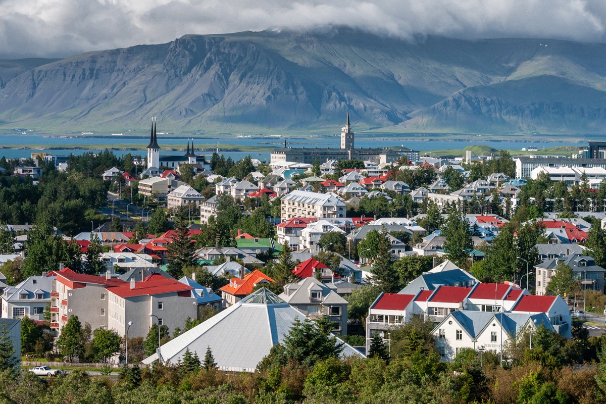 City panorama of Reykjavík with colourful rooftops, a church tower and mountains in the background
